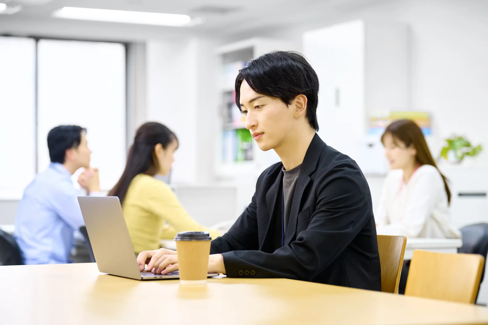 黒いジャケットを着てノートパソコンで仕事をする男性のイメージ