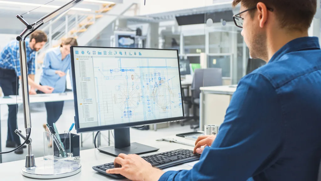 A staff member working while reviewing drawings and documents on screen